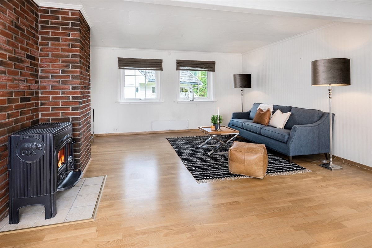 Stuen har parkettgulv, vegger med lys, stripete tapet og teglsteinskledt brannmur. Galleribilde