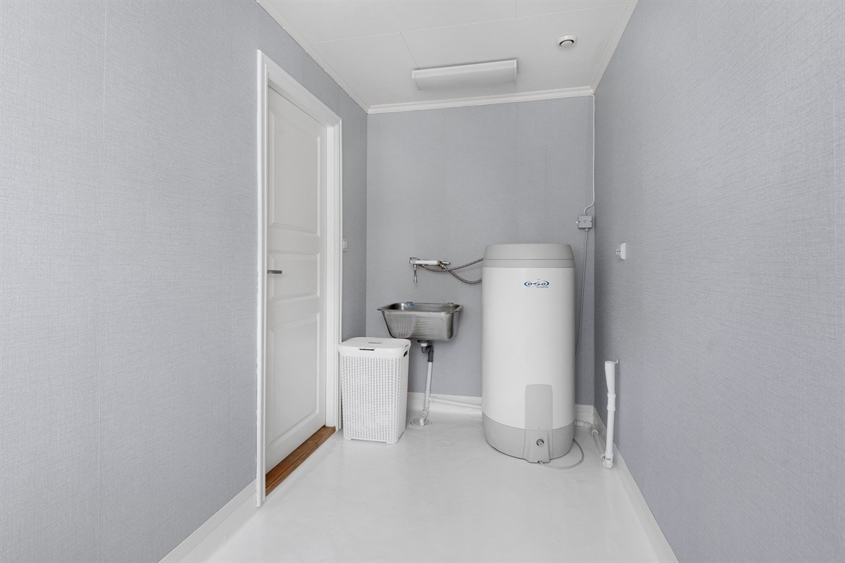 Vaskerommet i første etasje er et lyst rom med vindu i full størrelse. På gulvet er det malt vinylbelegg, mens veggene har lys tapet Galleribilde