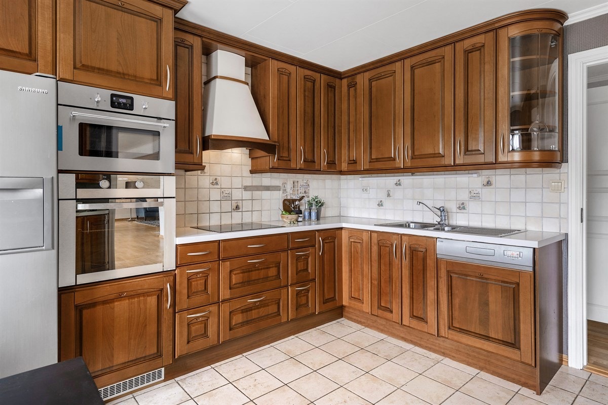 Innredningen har takhøye skap, profilerte fronter i gyllenbrunt heltre, noen vitrineskap med buet glass og lys benkeplate i laminat med nedfelt vaskekum. Stekeovn, ny mikrobølge- og dampovn fra 2018, induksjonstopp og oppvaskmaskin er integrert. Galleribilde