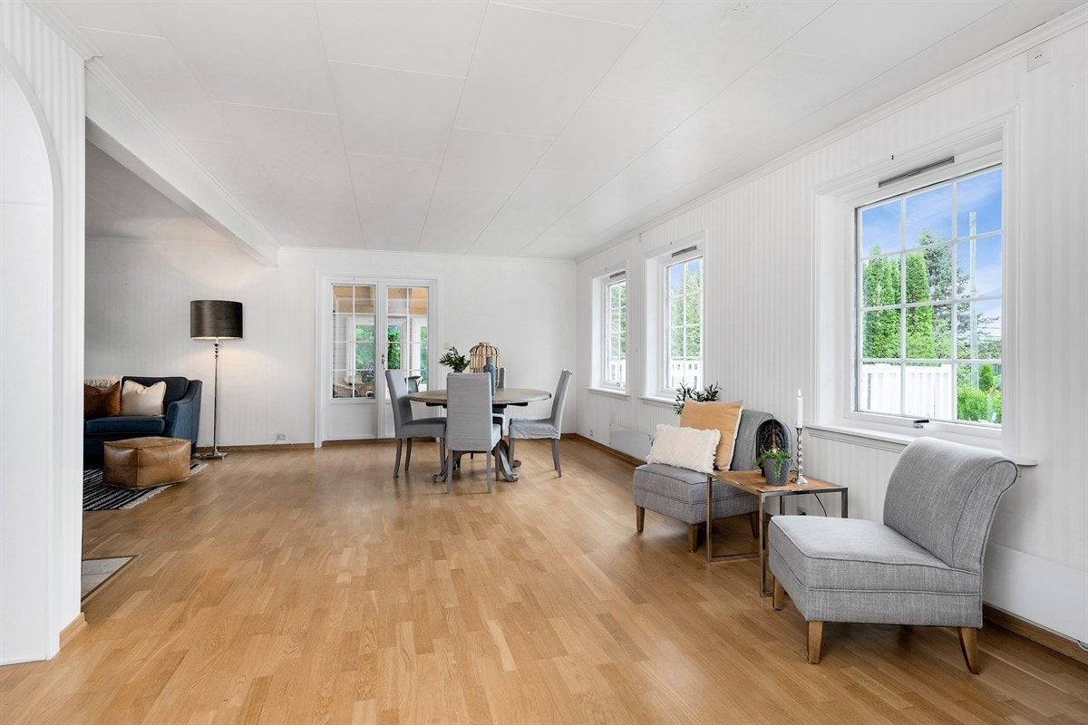 Stuen i første etasje er stor og lys med vinduer på to sider og tofløyet glassdør mot veranda med overbygg. Galleribilde