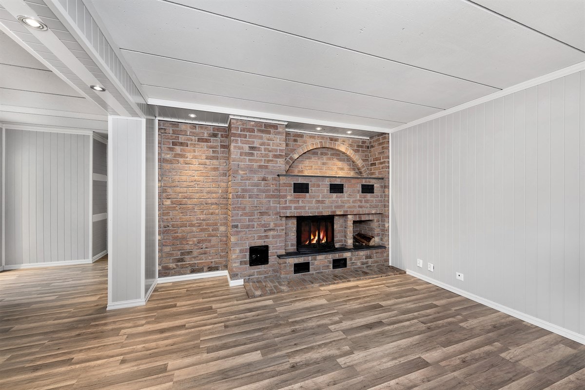 Stuen er romslig med pent laminatgulv, murt teglsteinspeis med innsats og godt med downlights langs himling. Galleribilde