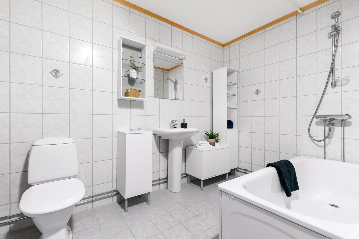Bad i underetasje er komplett fliselagt med gulvvarme, og er innredet med wc, dusj, badekar, servant med speil, skyllekar med benkeplate, samt opplegg for vaskemaskin