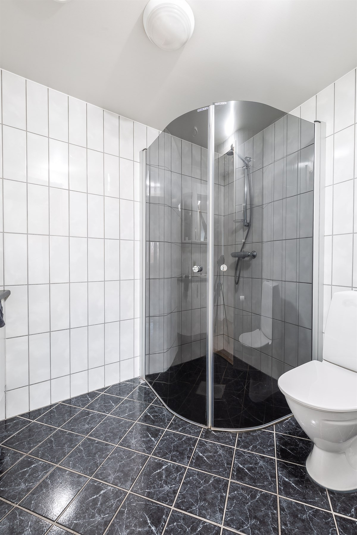Badet er komplett fliselagt med dusjhjørne, wc og dobbelservant