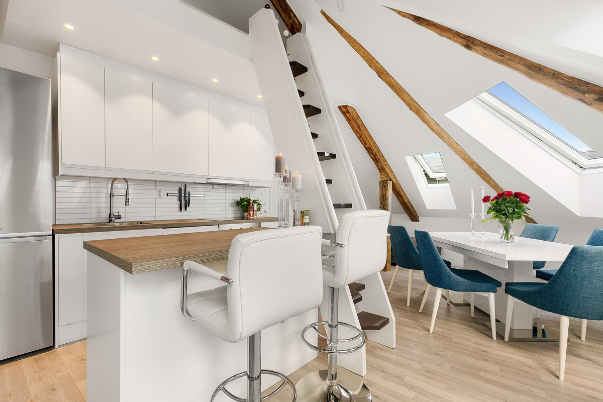 Moderne kjøkken med et lekker stilrent design - hvite glatte fronter, flis over benk, kjøkkenøy og stor kum.