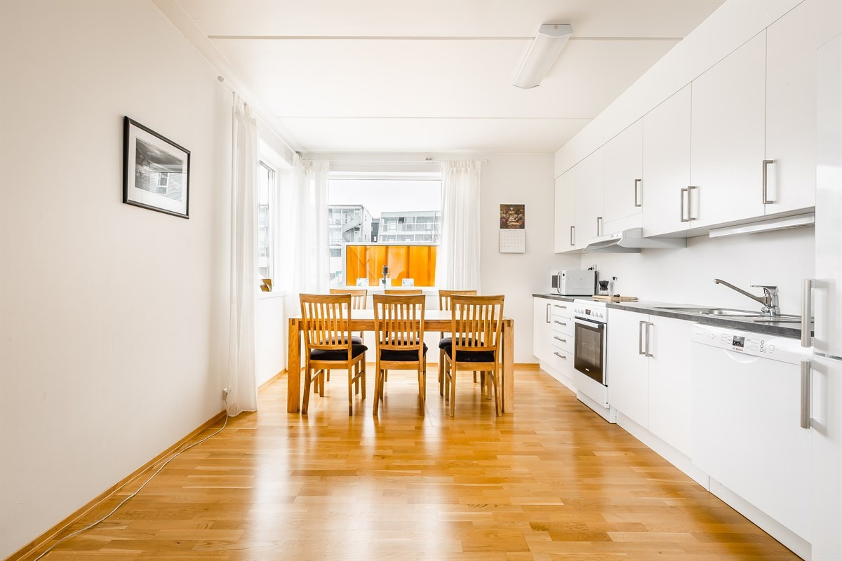 Hvit, moderne innredning med takhøyeskap og gjennomgående lysinnslipp