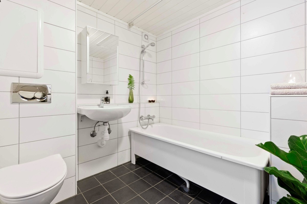 Bad/vaskerom i kjelleretasje med badekar, wc og servant Galleribilde