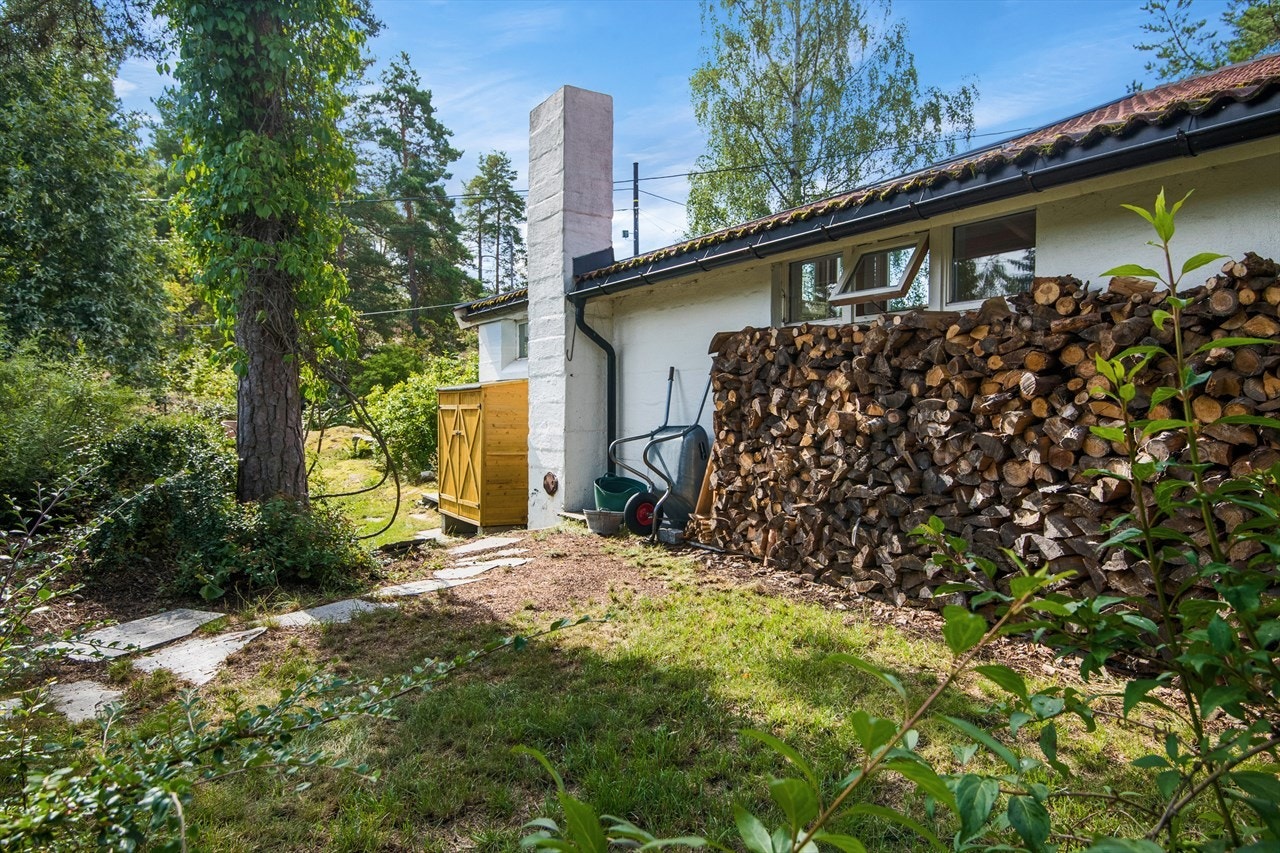 Bak huset er den en liten redskapsbod og en medfølgende stabel med ved. Galleribilde