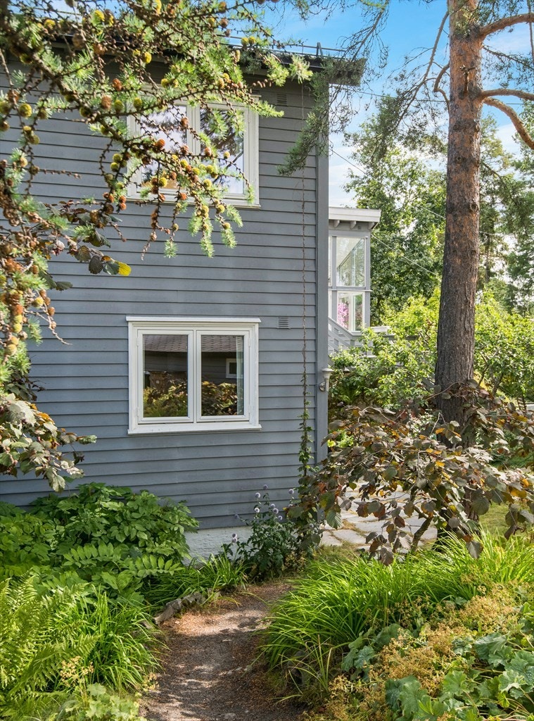 Stien inn fra gaten med et praktfullt lerketre, furu og blodhassel, gir følelsen av å passere en portal inn mot hagen og huset. Galleribilde