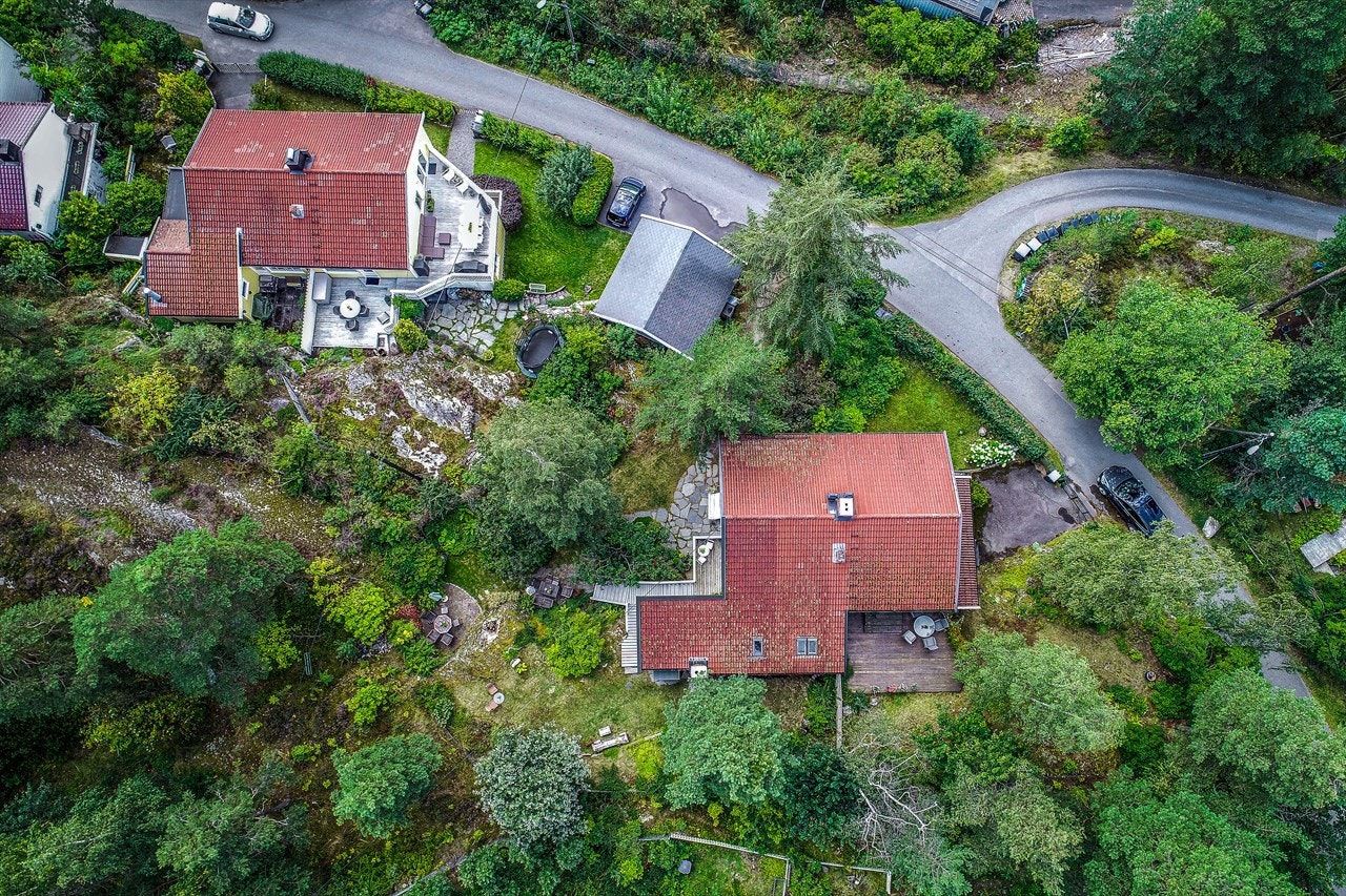 En vakker naturtomt med fjellknauser og naturlig kupering omgir huset. Gatene rundt er svært lite trafikkert. Galleribilde