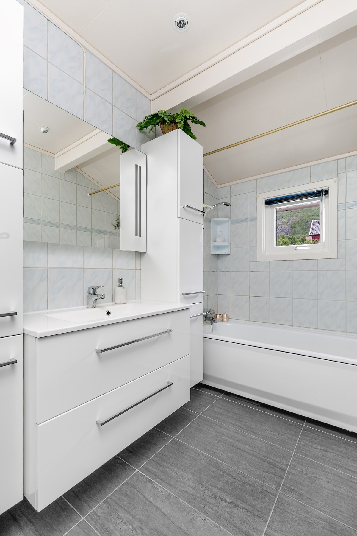 Lekkert baderom med badekar sokkelflis, gulvvarme og godt med lagringsplass