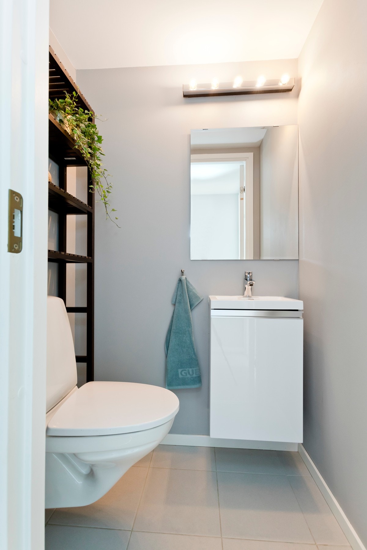 Toalettrom utstyrt med vegghengt toalett, innredning med heldekkende servant og speil med lys over. Galleribilde