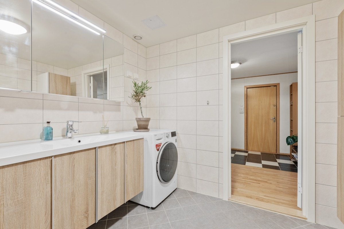 Delikat innredning fra Foss Bad med god skapplass. Opplegg for vaskemaskin. Galleribilde