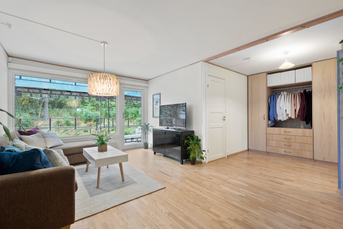 Stue og balkong vender ut mot et fredelig grøntområde og skog. Galleribilde