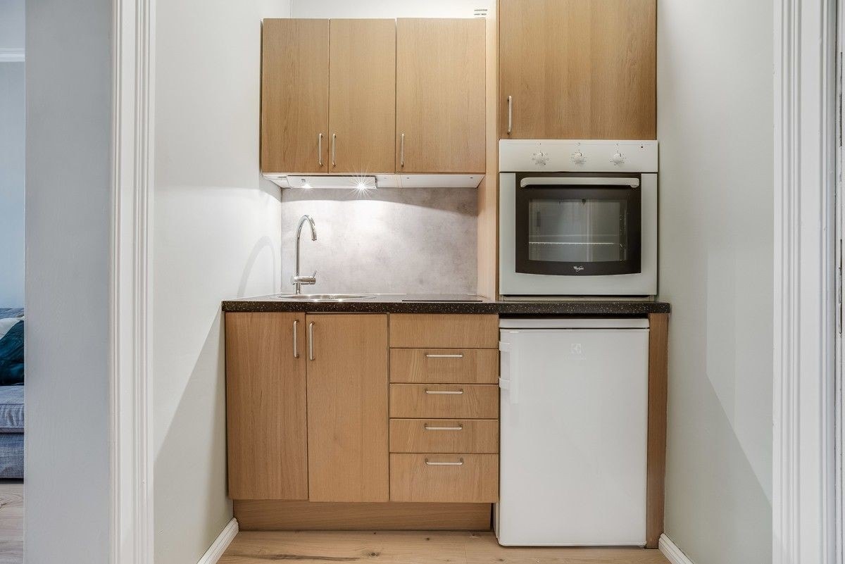 Praktisk kjøkkeninnredning med mørke fronter og lys under overskap Galleribilde