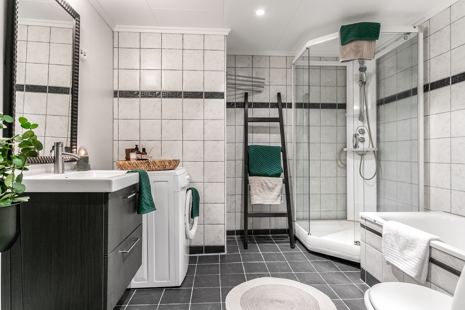 Leilighetens bad er på 6.9 kvm. Badet er flislagt med varme i gulv og er innredet med servant med underskap, gulvmontert toalett, dusjkabinett og garnityr på vegg og opplegg for vaskemaskin. Galleribilde