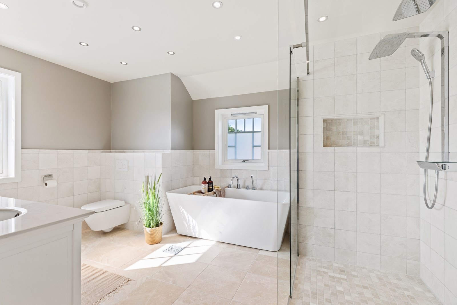 Badet er innredet med dobbeldusj med fast herdet glass, store dusjhoder og hånddusjer, servantinnredning med lekker heldekkende servantplate, underlimt porselensservanter samt skap, skuffer under. Det er montert vegghengt wc på og vannsentral på badet. Galleribilde