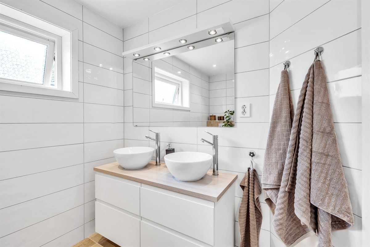 Badet i andre etasje har en stilren innredning med hvite skuffefronter og laminert benkeplate med to toppfestede servanter, samt høyskap. Galleribilde