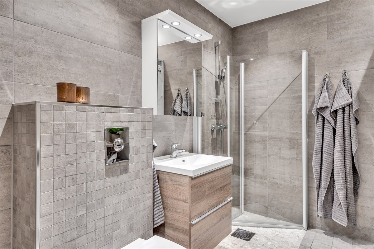 Rommet har vegghengt toalett, et moderne servantskap og dusjhjørne med innfellbare glassdører. Galleribilde