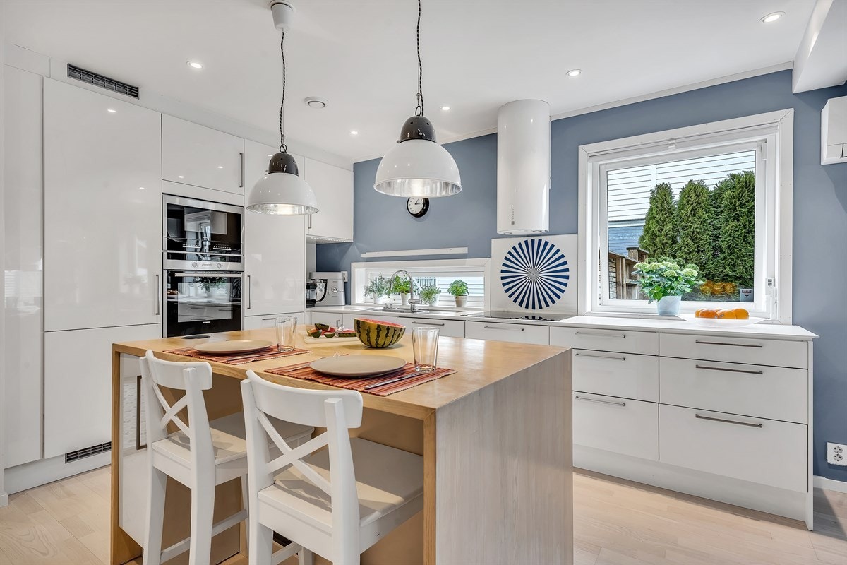 Kjøkkenet har en moderne og lekker innredning med hvite høyglansfronter, takhøye skap og hvitlaminerte benkeplater, samt kjøkkenøy med to spiseplasser. Galleribilde