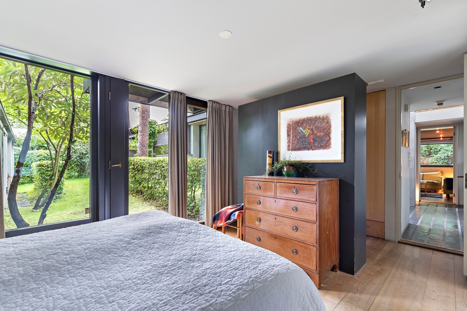 Vinduer fra gulv til tak og utgang til hage skaper en flott atmosfære på soverommet Galleribilde