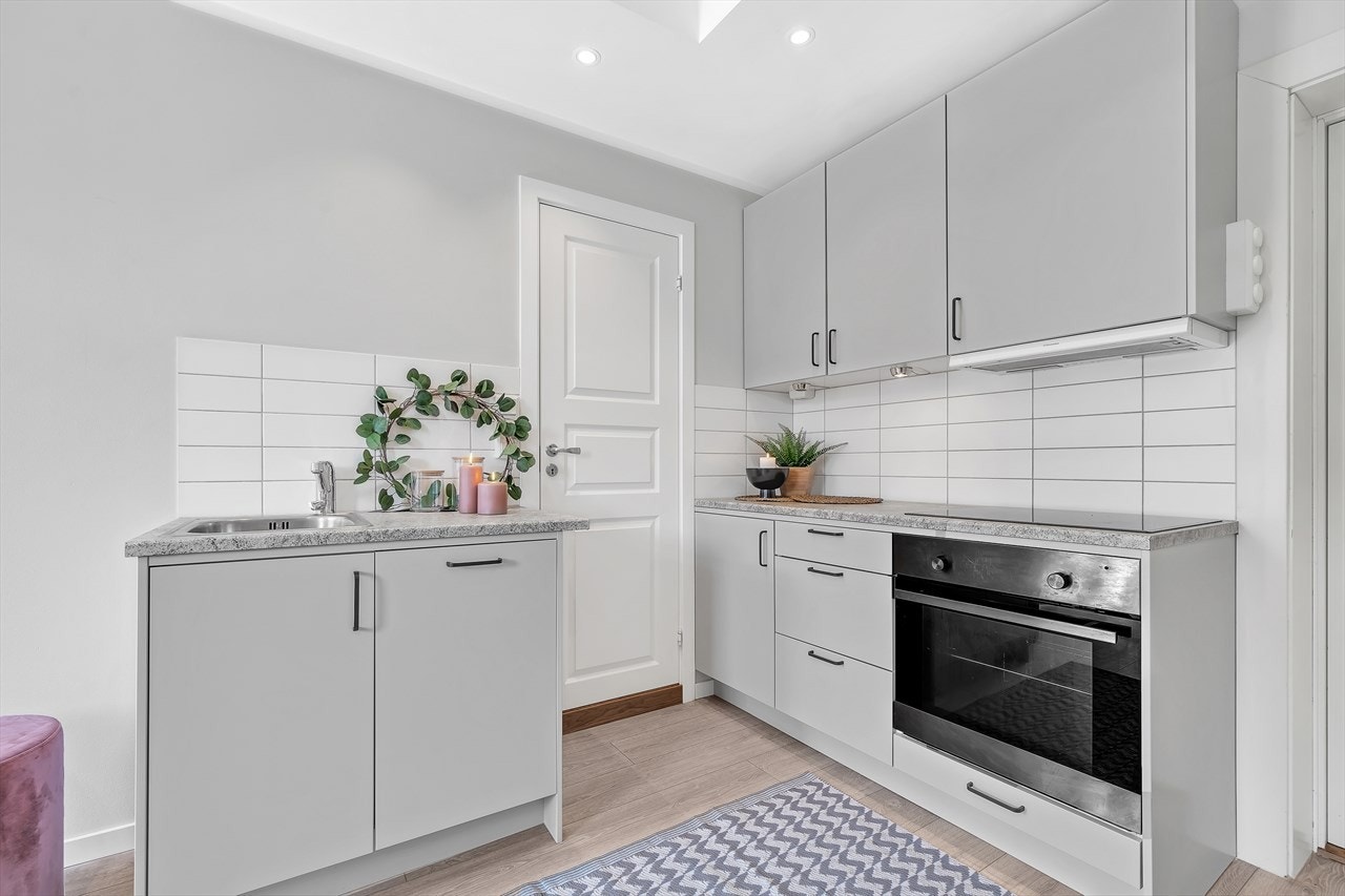 Kjøkken med integrert komfyr med platetopp, kjøle-/fryseskap og oppvaskmaskin. Galleribilde