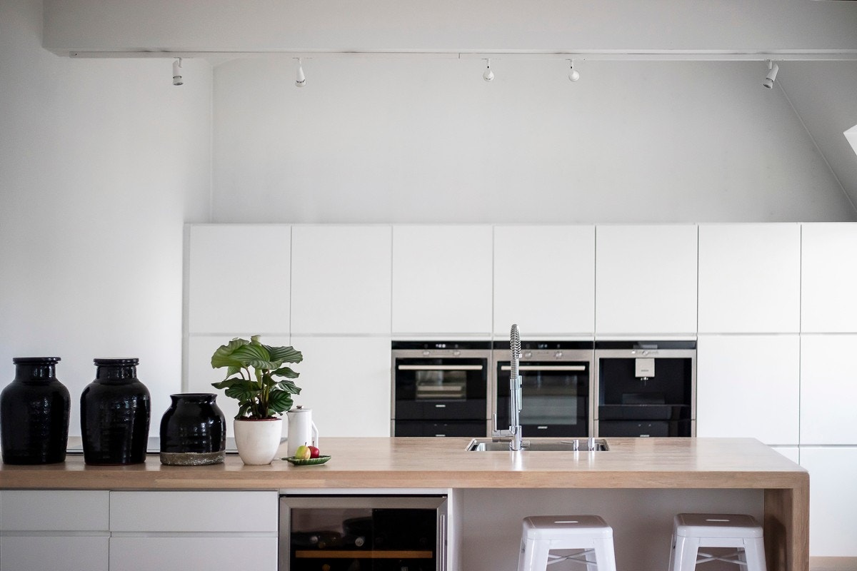 Mot stuen står en bred og lang barløsning med sitteplasser, underskap og et integrert vinskap. Galleribilde