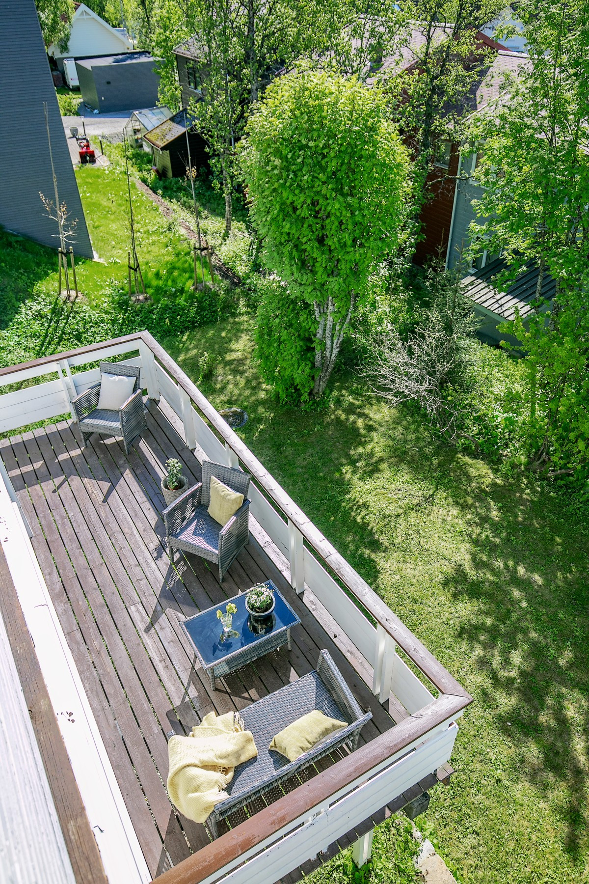 Stor vest- og sydvendt veranda i tilknytning til terrasseplatting mellom boligen og garasje, med utgang fra soverom/stue i 1. etasje