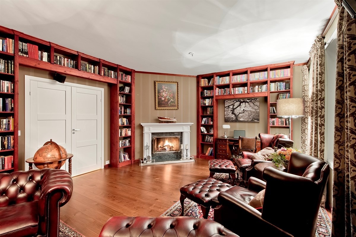 Rommet har doble dører inn fra trappegangen og veggene er dekket av pen tapet og store, plassbygde bokreoler. Galleribilde