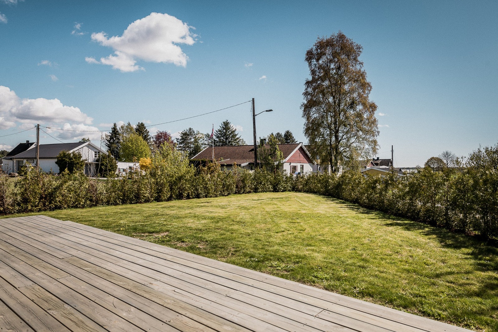 Barna kan leke og hygge seg i hagen som er pent innrammet av en voksende hekk. Galleribilde