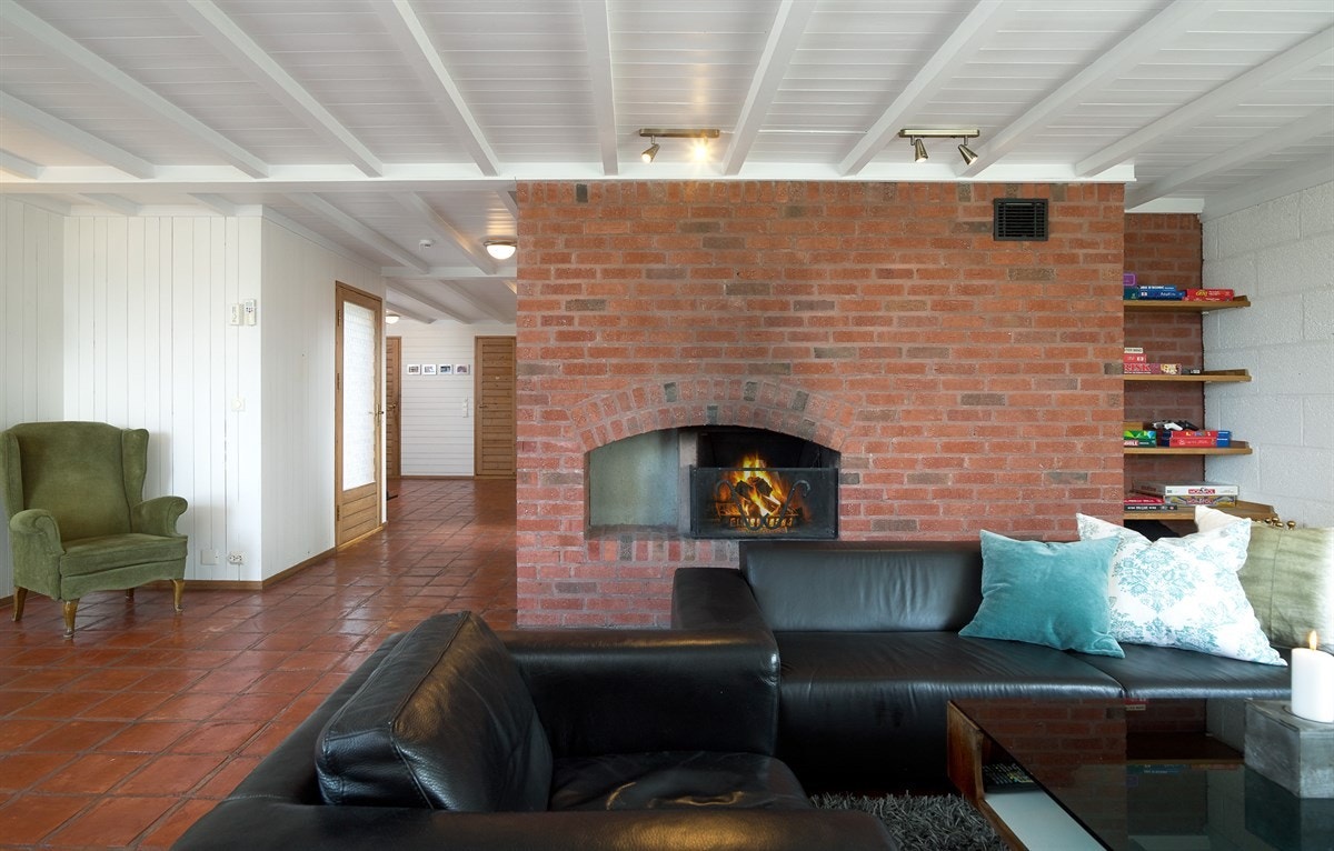 Stuen i underetasjen har et fint peisarangement i tegl. Galleribilde
