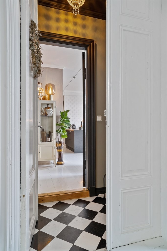 En høyreist, dobbelfløyet tredør åpner for entreen som har lekkert sjakkmønstret gulv. Galleribilde