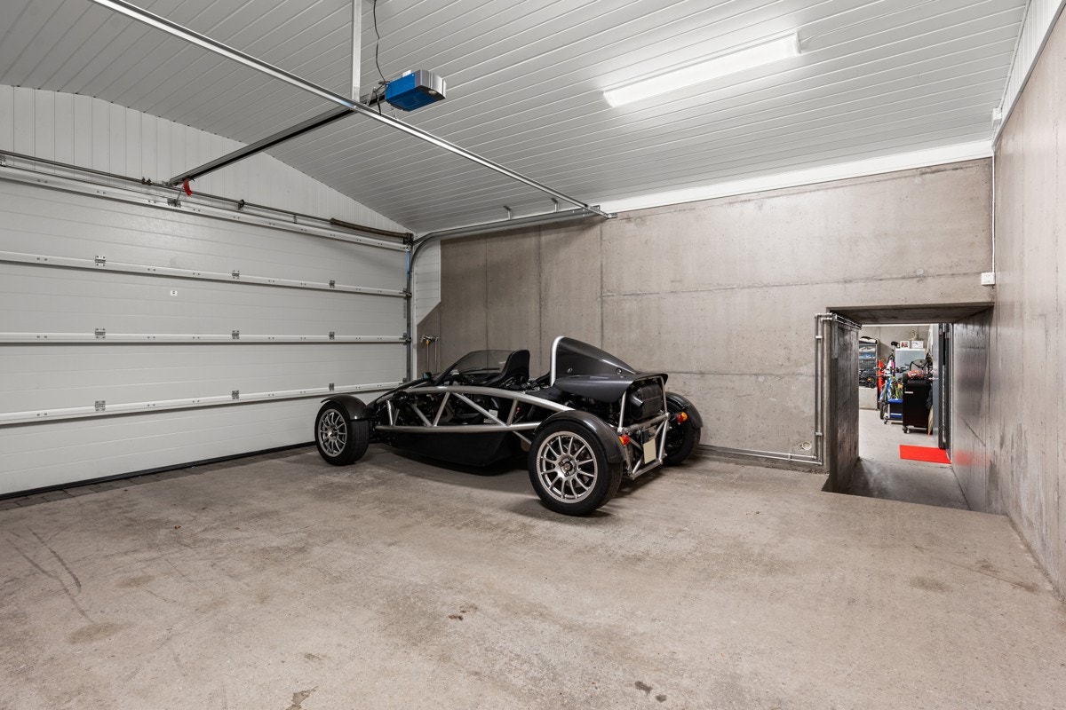 Dobbeltgarasje innvendig målt til ca. 32 m². Underjordisk gang fra garasjerom til boligen kjelleretasje. Galleribilde