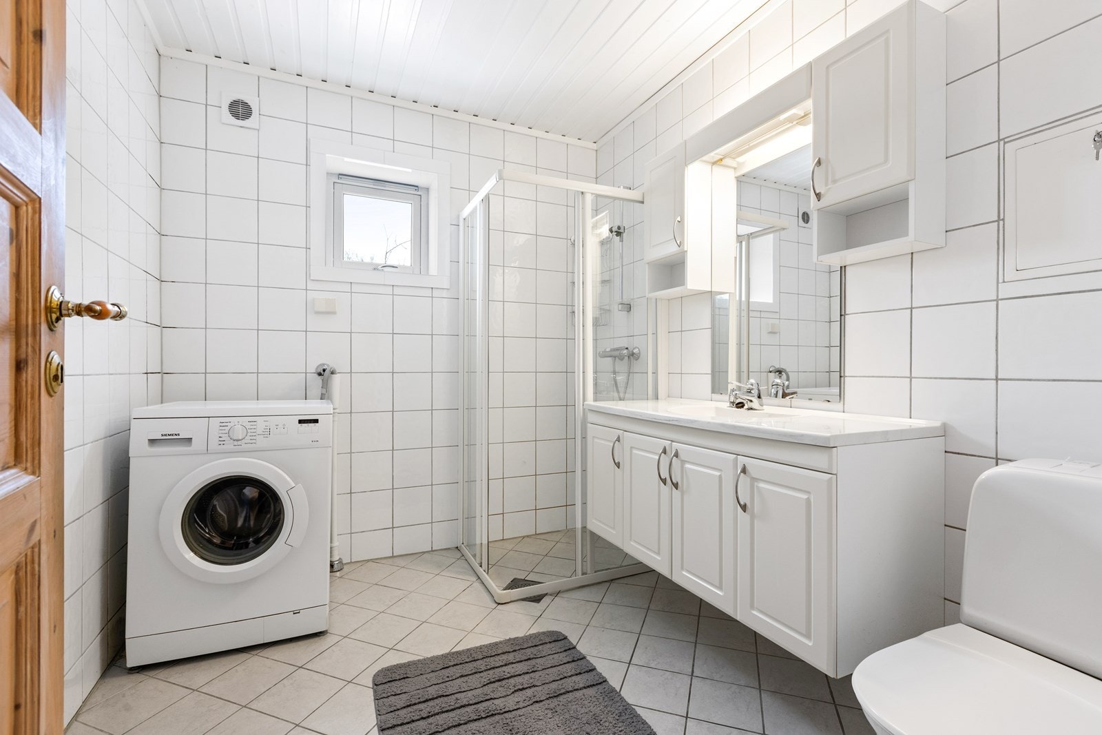 Badet i gjesteleiligheten er fra 2004 og har flissatte overflater, servantskap, dusjhjørne, toalett og opplegg for vaskemaskin. Galleribilde