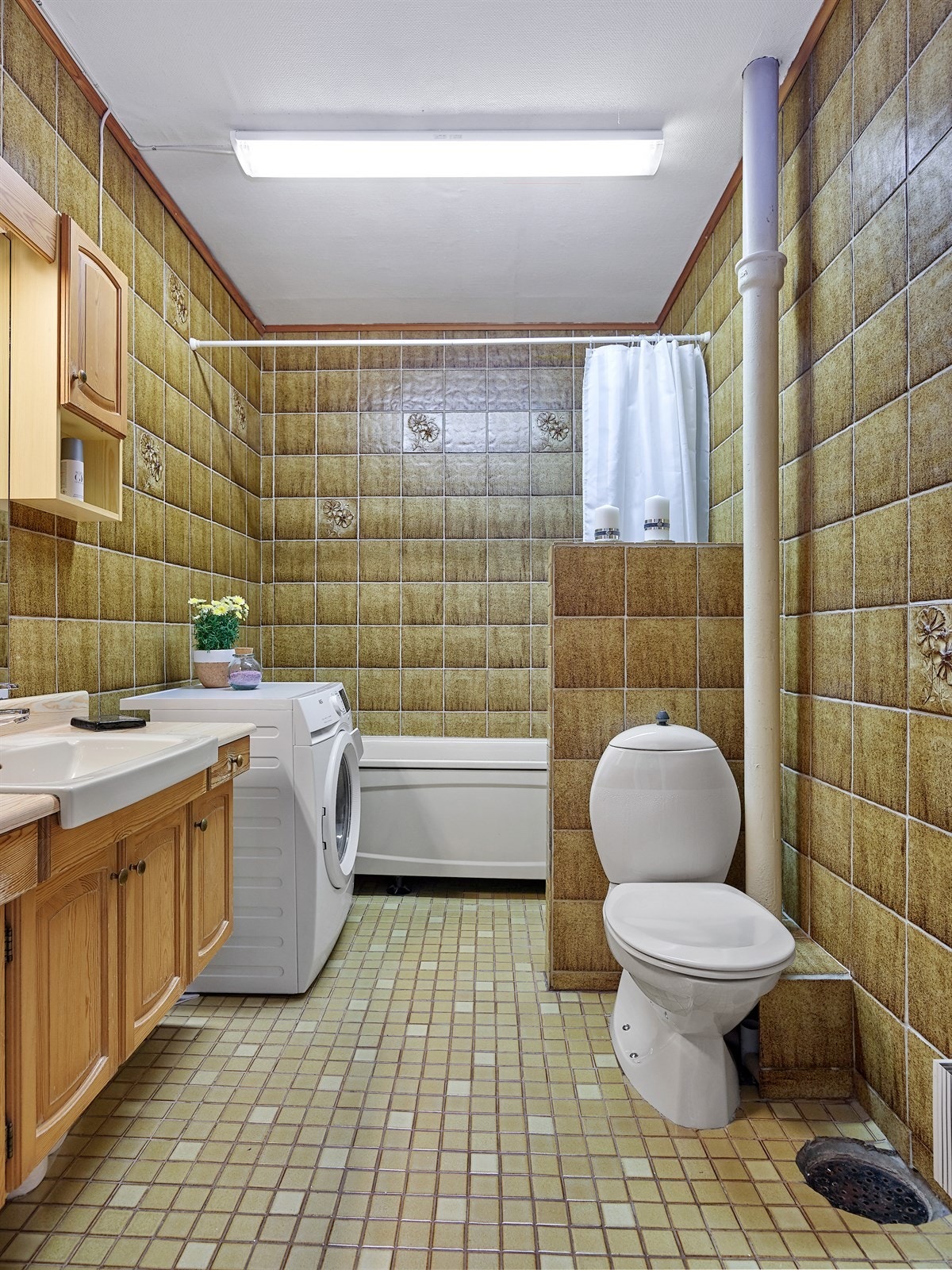 Stort og eldre bad med badekar og opplegg til vaskemaskin. Galleribilde