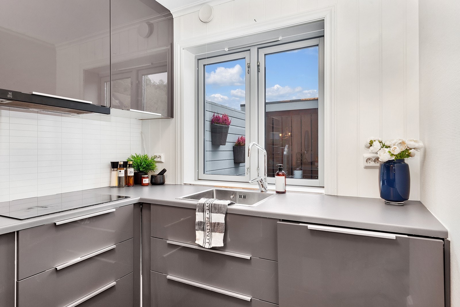 Flott utført kjøkken med fronter i grå høyglans og lysere grå benkeplate Galleribilde