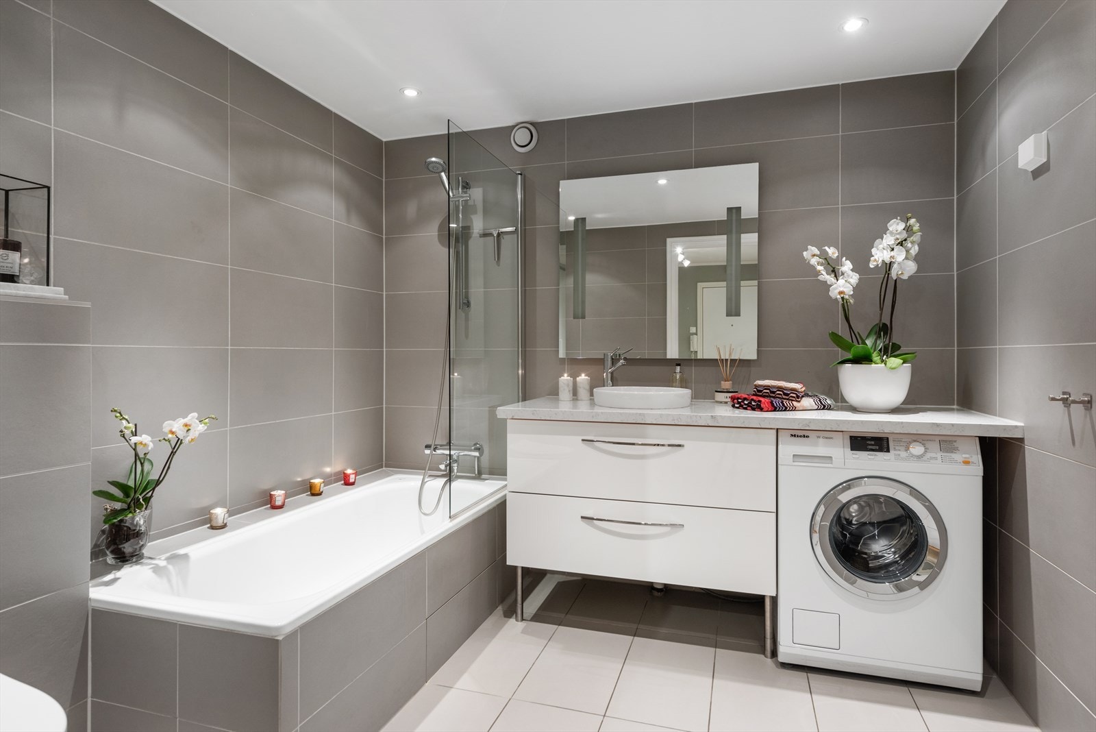 Pent, innbydende og romslig flislagt baderom som ble overflateoppusset i 2012. Ny benkeplate i stein i 2018. God oppbevaringsplass i skuffer og skap. Opplegg til vaskemaskin/tørketrommel. Galleribilde