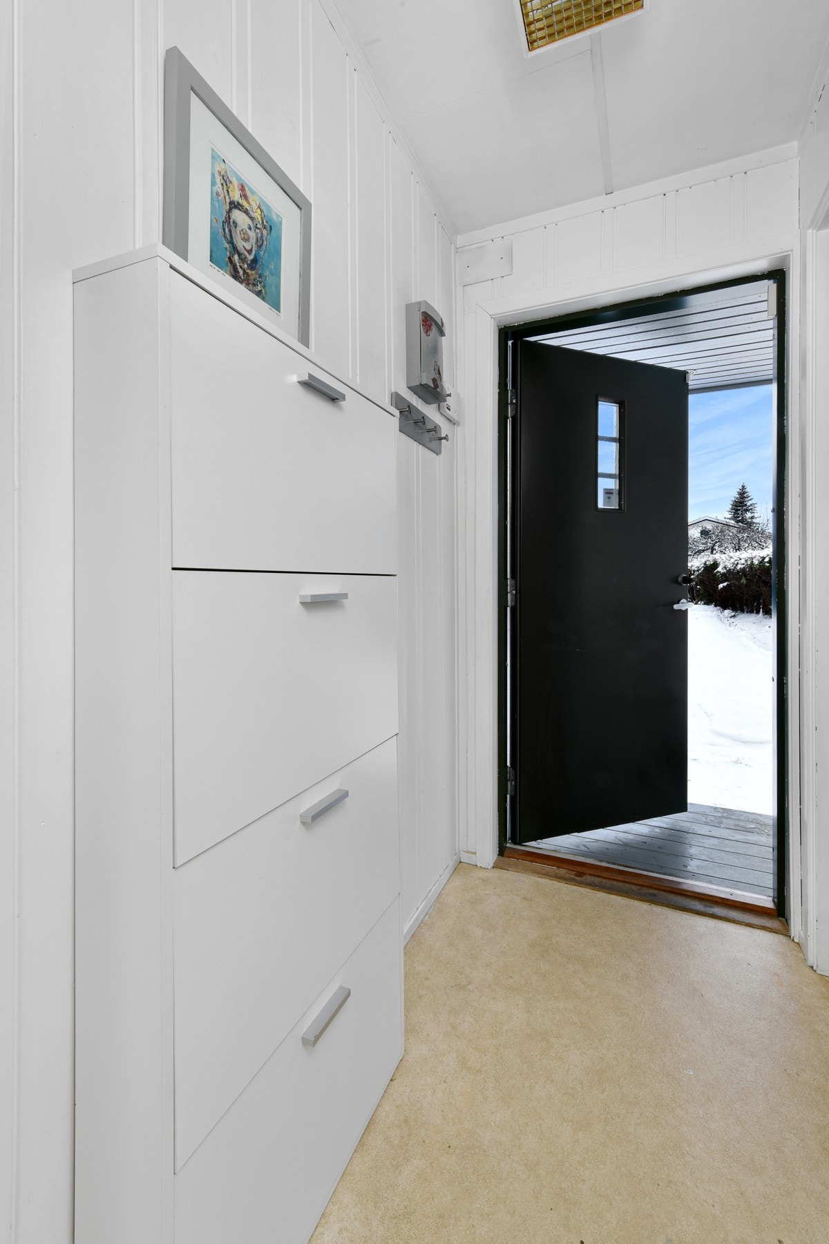 Vindfanget har lyst vinylbelegg på gulvet og hvitmalte panelvegger. Galleribilde