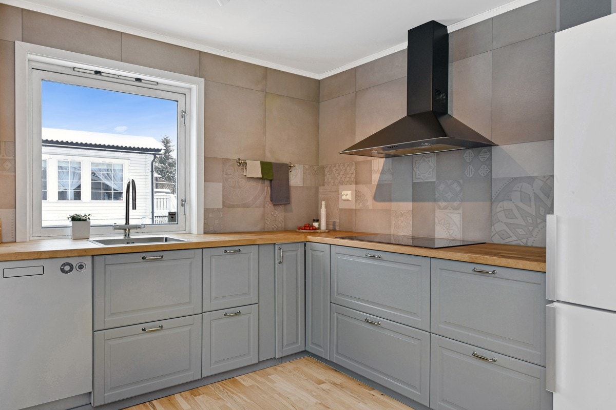 Ikea-innredningen er tidsriktig med grå, profilerte fronter, vitrineskap og benkeplate av tre. Galleribilde