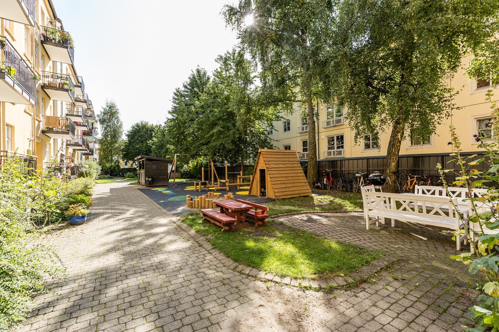 Skjermet bakgård med sittegrupper, lekeapparater, sykkeparkering og felles grill til benyttelse. Galleribilde