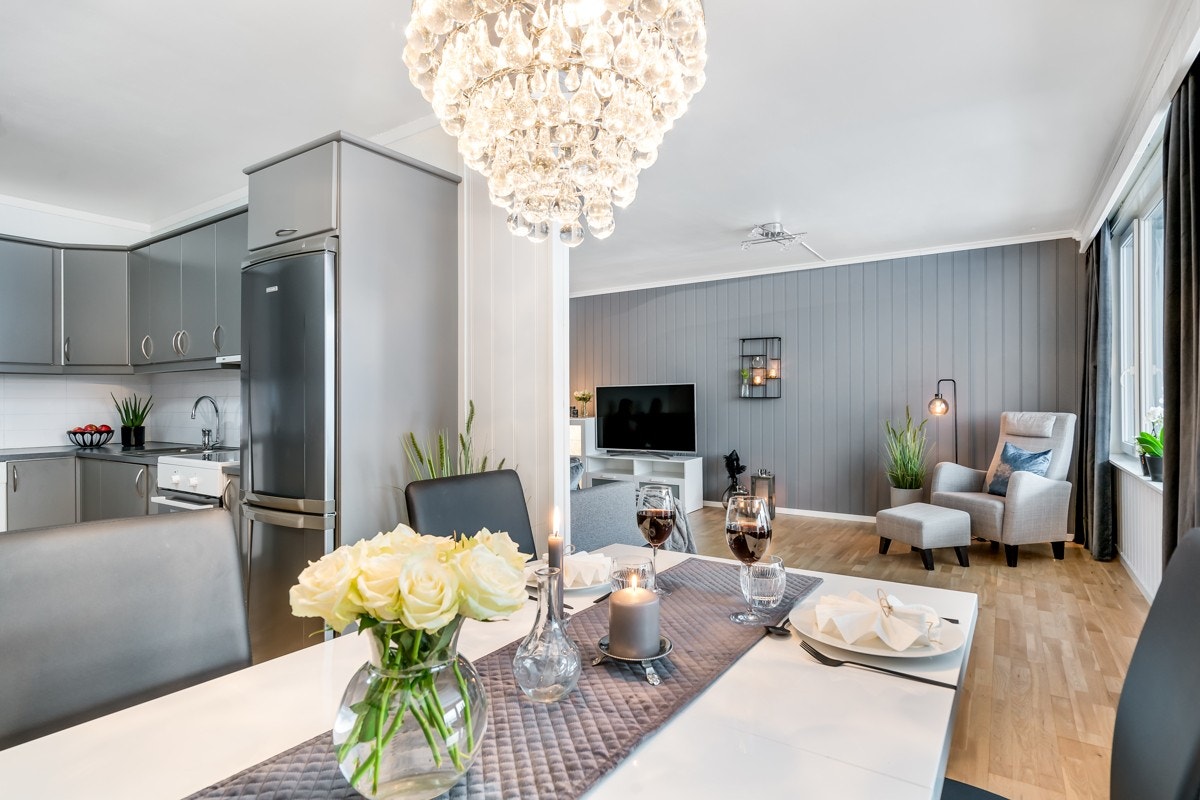 Stuens overflater er tidløse, det er parkettgulv og panelte vegger som nylig er malt i hvitt, supplert av en kontrastvegg i grått. Galleribilde