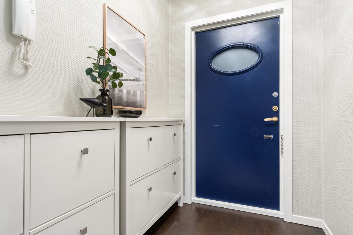 - En nydelig blåmalt inngangsdør med ovalt glassfelt gir en fin kontrast til de lyse overflatene. Dørtelefon med portåpner til gatedøren - Galleribilde