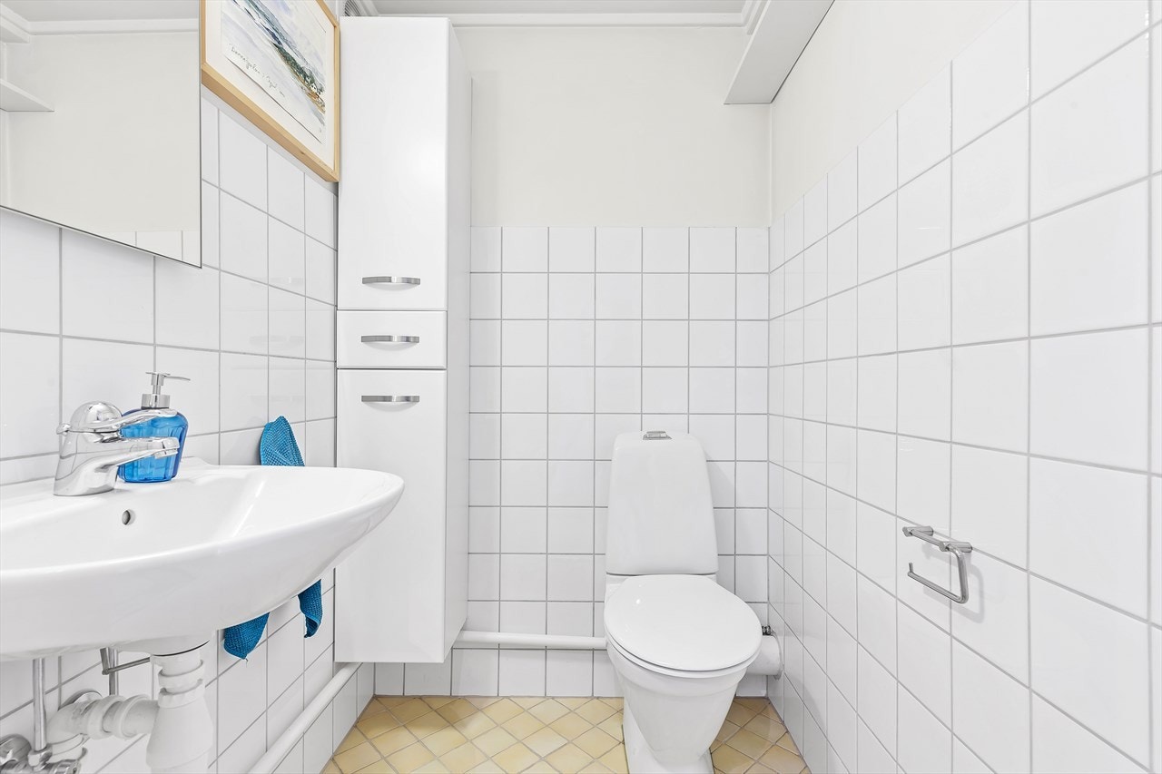 WC-rom i kjeller med flislagt gulv og varmekabler. Servant. Toalett. Elektrisk avtrekksvifte. Wc-rommet ble pusset opp i 2004. Galleribilde