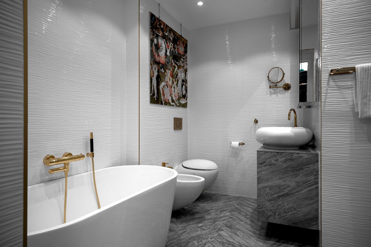 Lekkert baderom med keramiske fliser lagt i fiskebensmønster. Det er både badekar og separat dusj. Galleribilde