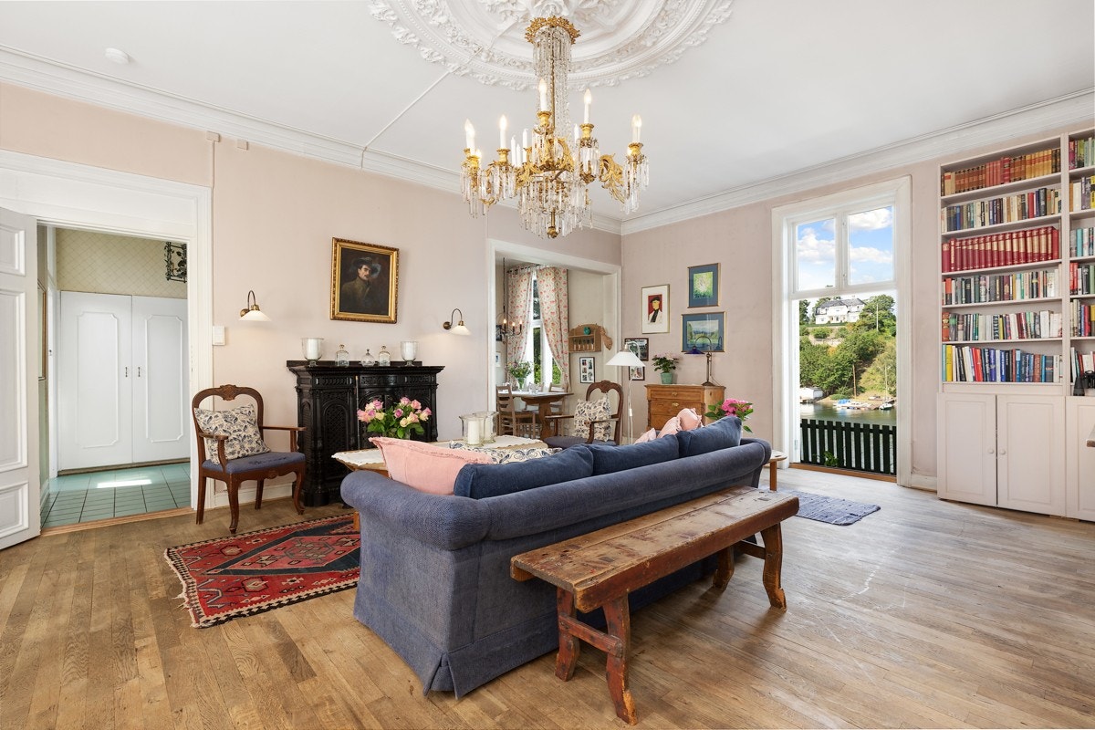 Original, utsmykket støpejernspeis med topplate i polert stein. Stuen har gulvbord i eik, malte veggplater, samt en fastmontert innredning med benkeskap og hyller. Det er god plass for sittegruppe og møblement. Galleribilde