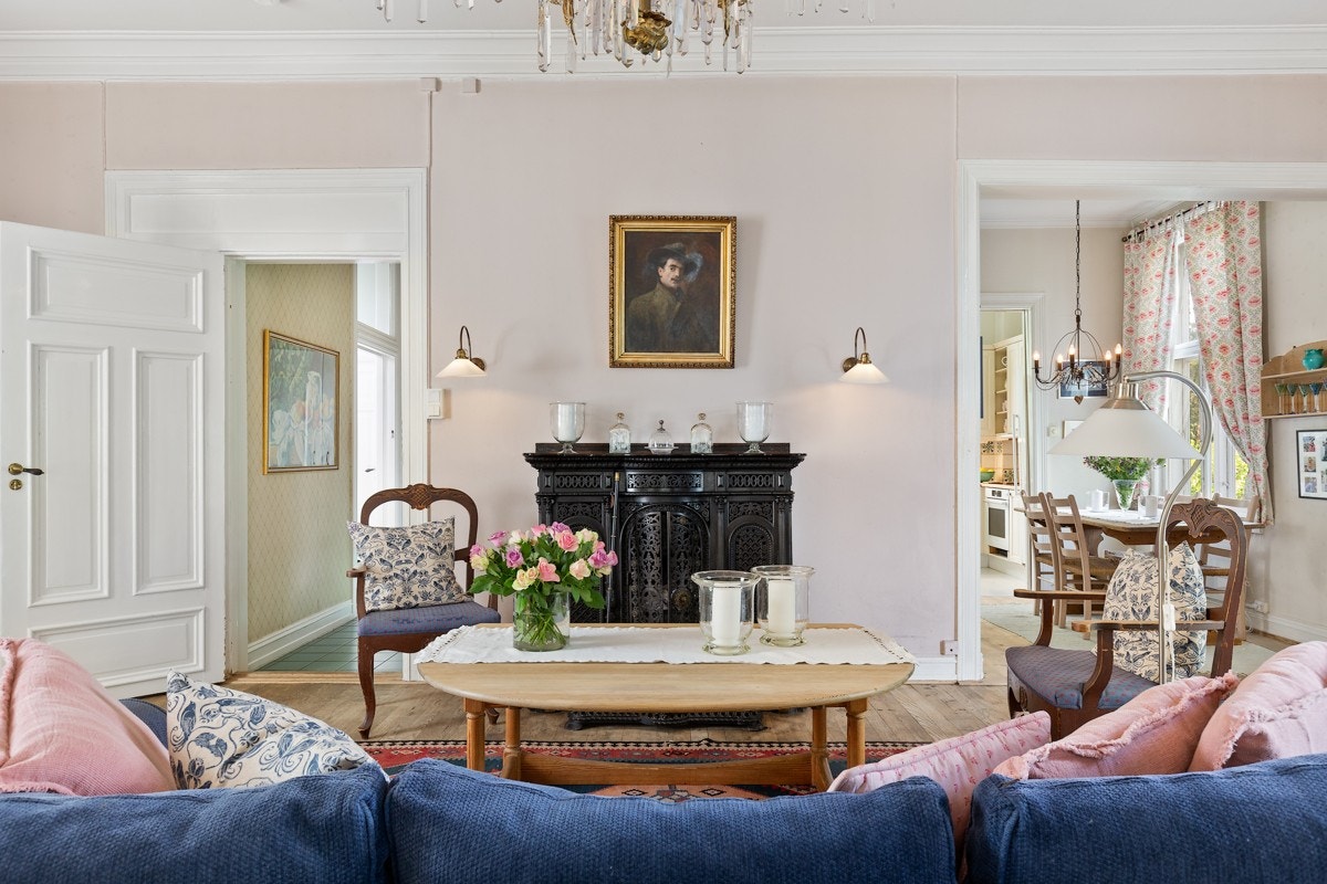 Original, utsmykket støpejernspeis med topplate i polert stein. Stuen har gulvbord i eik, malte veggplater, samt en fastmontert innredning med benkeskap og hyller. Det er god plass for sittegruppe og møblement. Galleribilde
