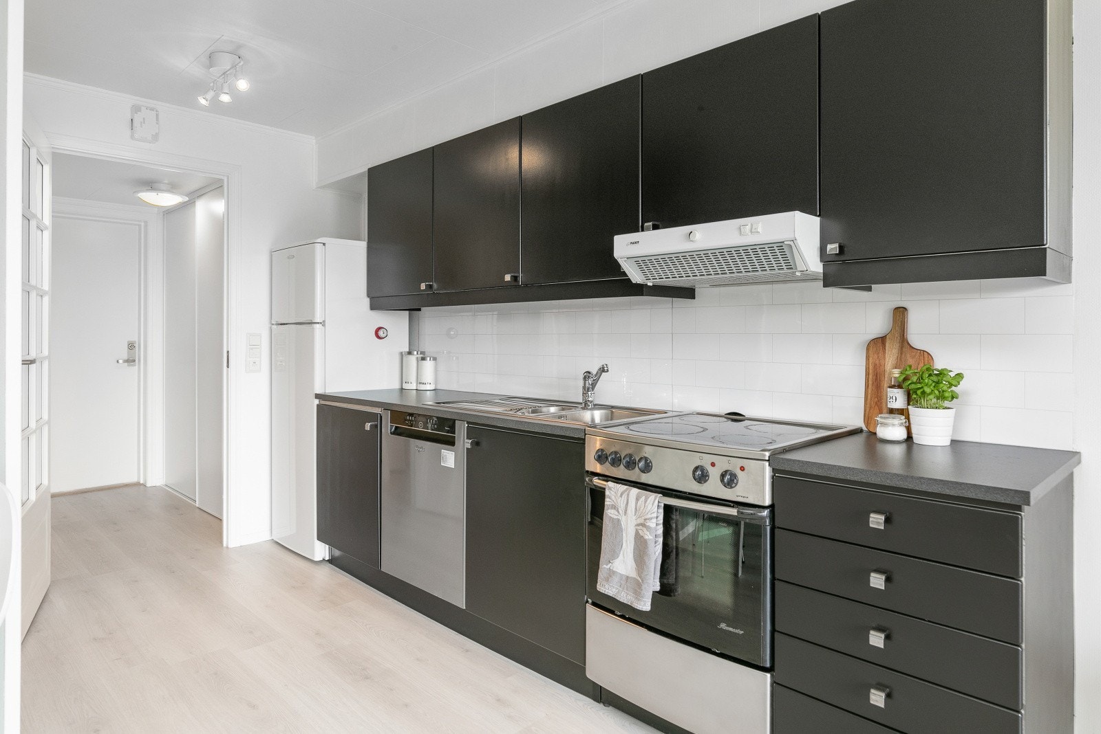 Kjøkken med kjøleskap/fryser, oppvaskmaskin og komfyr Galleribilde