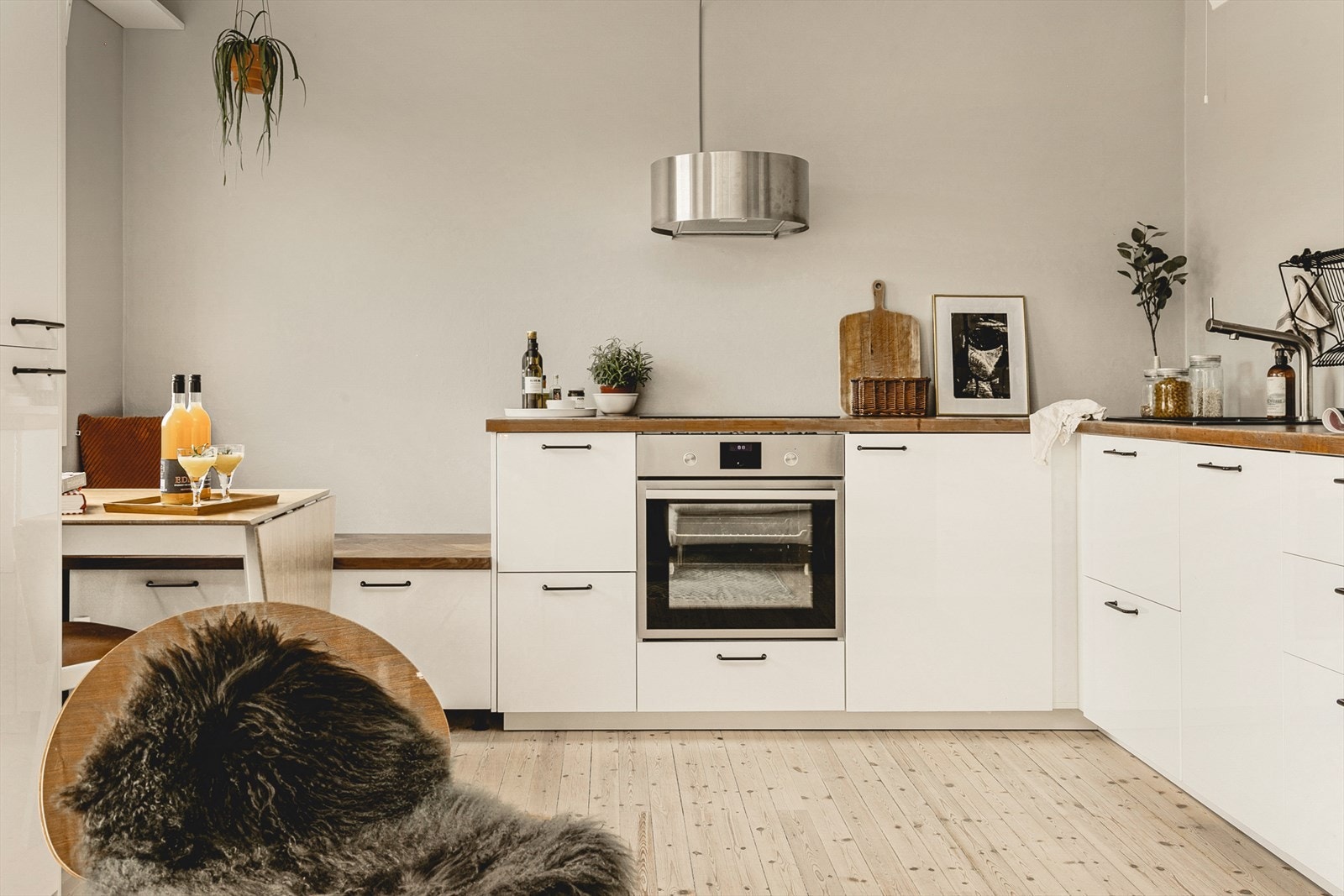 Kjøkkeninnredning med lyse glatte høyglansfronter og laminerte benkeplater. Innredningen inkluderer bl.a. ventilator med kullfilter, induksjonstopp og stekeovn. Galleribilde