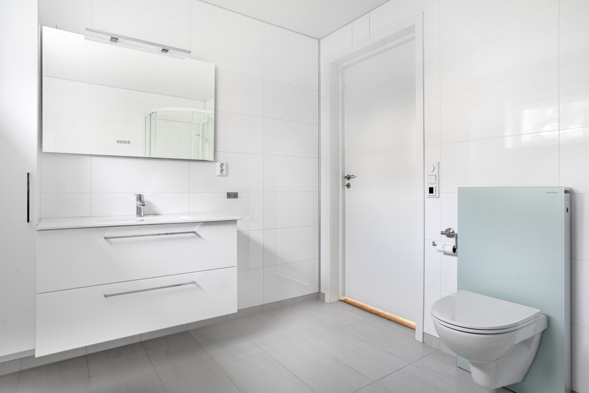 Romslig baderom med lys og moderne baderomsinnredning med gode oppbevaringsmuligheter