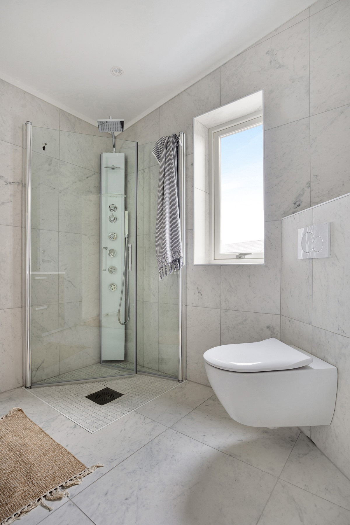 Badet i 2.etasje har vegghengt toalett, vegghengt dusj med store glassdører og servant m/innredning