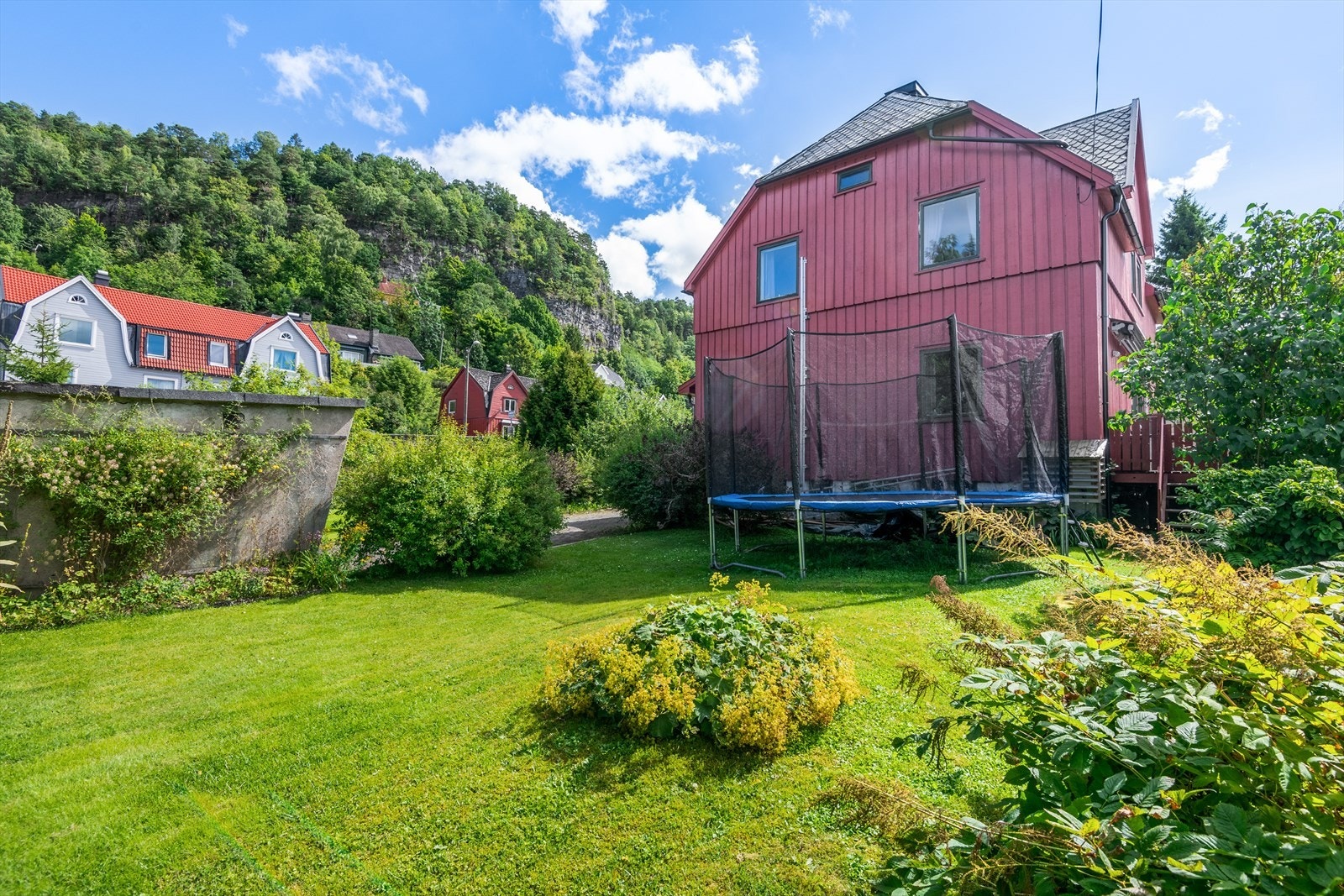 Solrik tomt som er pent opparbeidet med plen og beplantninger. Galleribilde